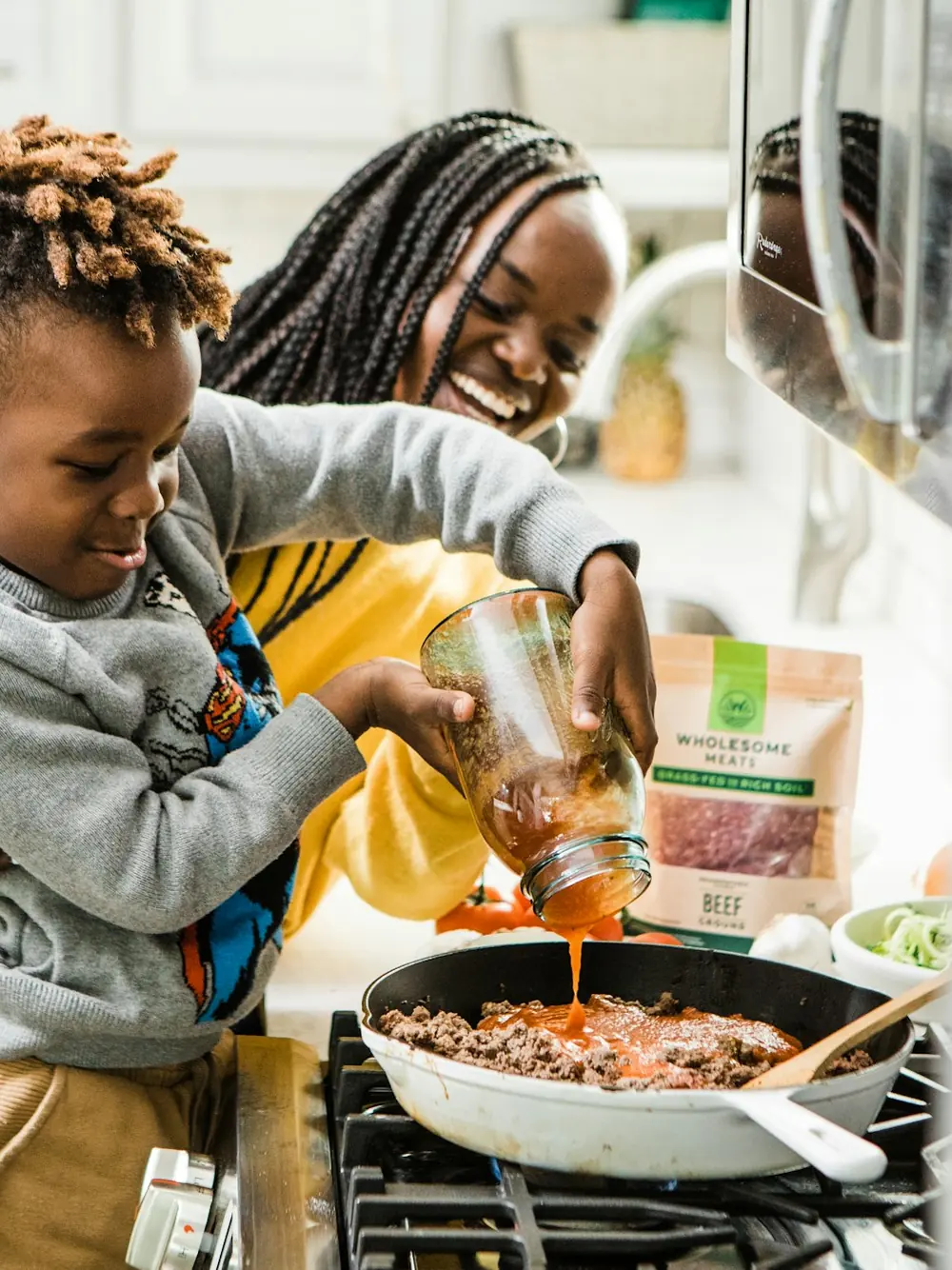 A parent and child cooking together at the stove