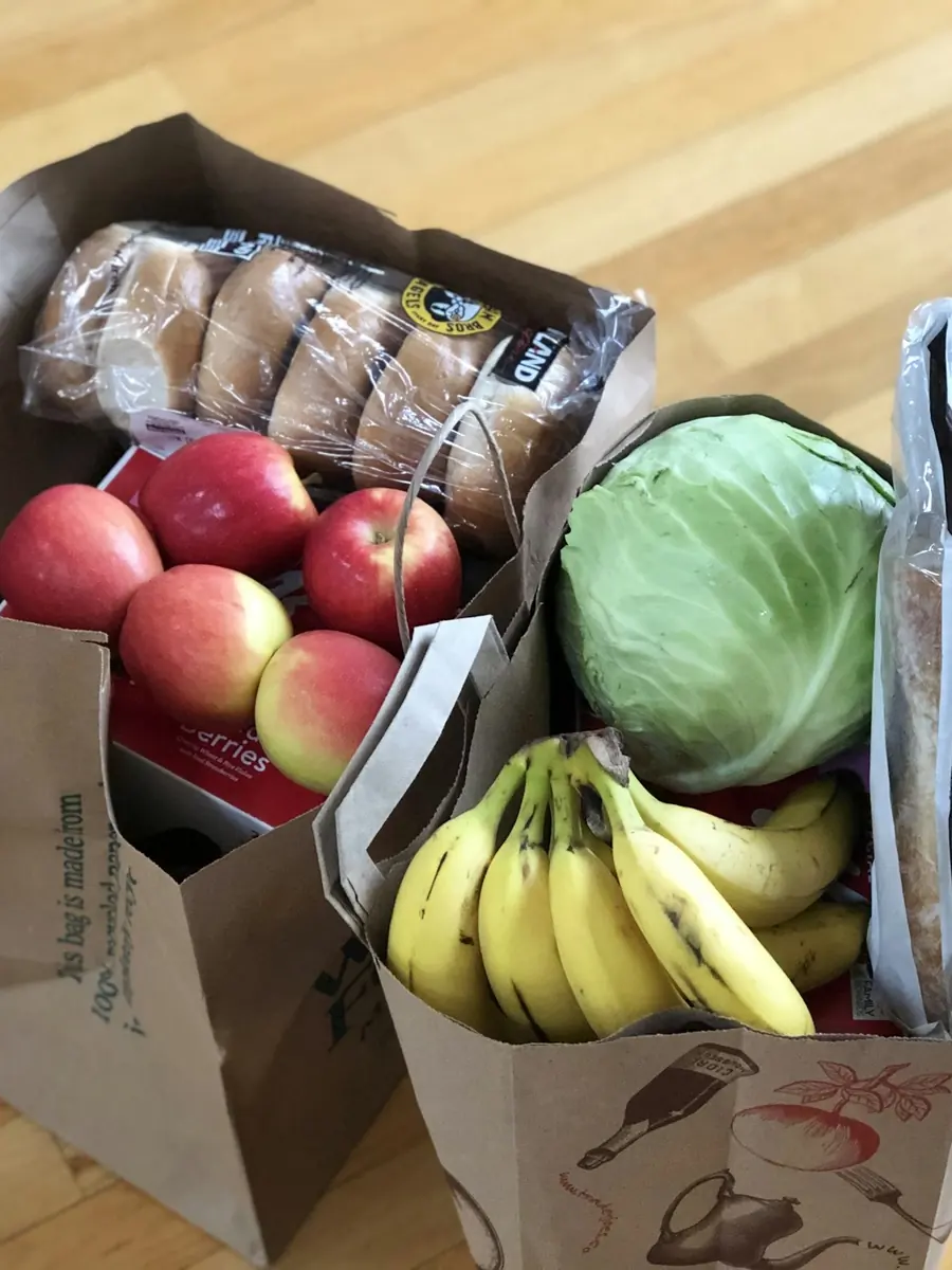 A paper grocery bag with apples, bananas and cabbage